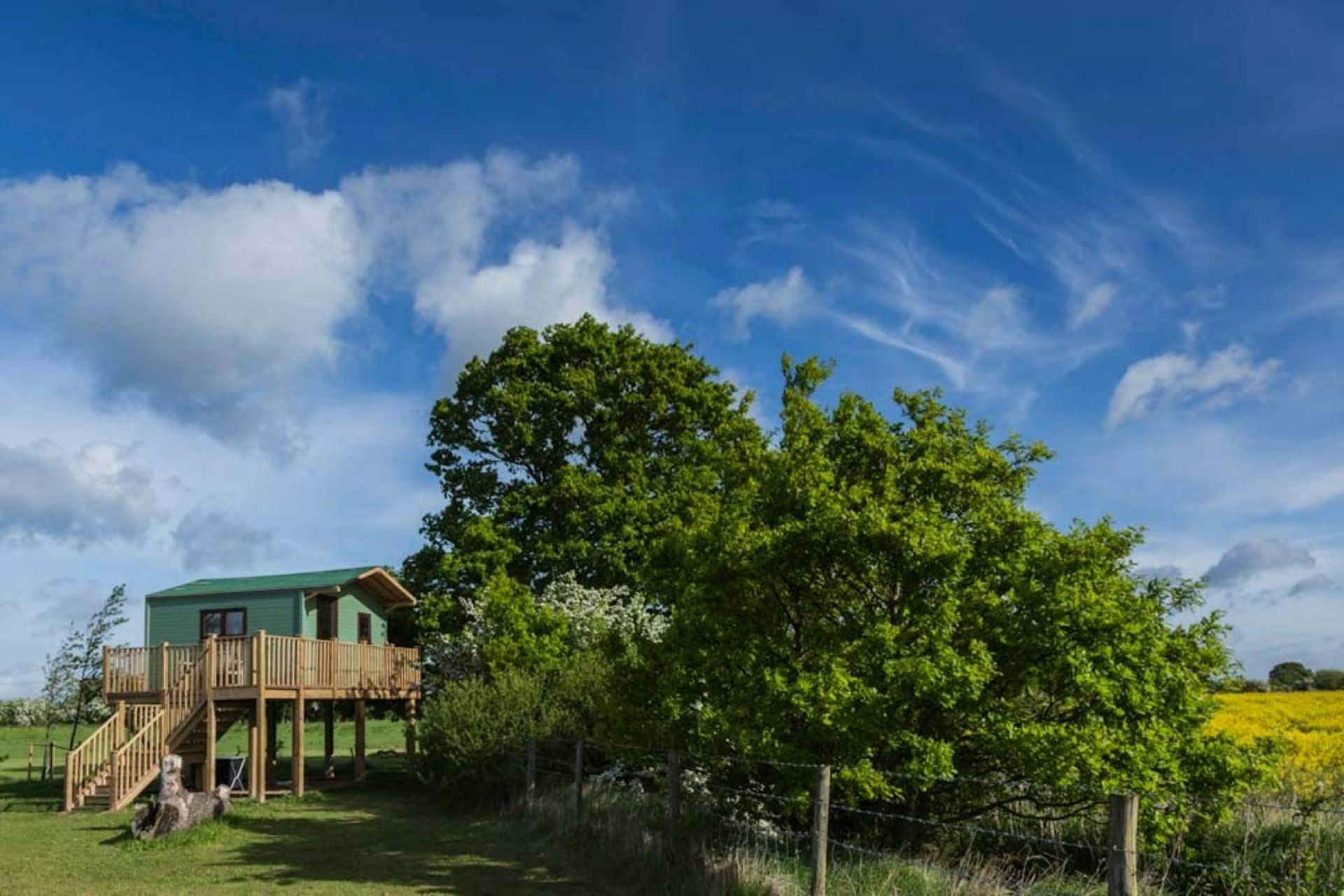 A freestanding wooden house nestles beside some trees